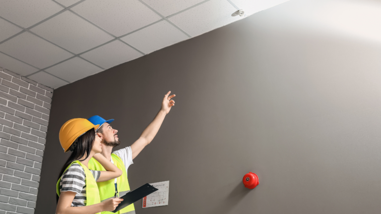 Two fire professionals make sure a business's fire sprinklers are in line with laws and regulations for fire safety. 