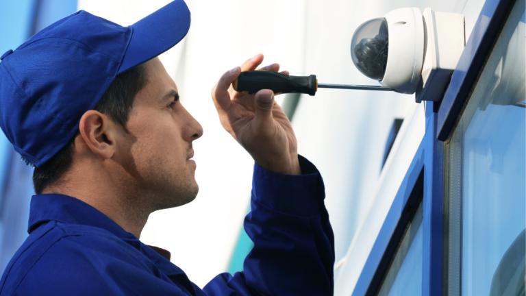 Wireless camera being installed on the side of a building by security professional. 